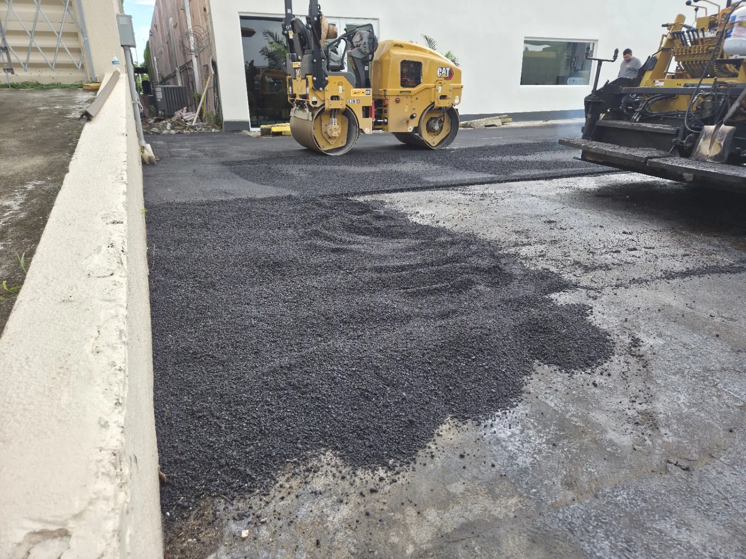 Roller compacting fresh asphalt during commercial paving work