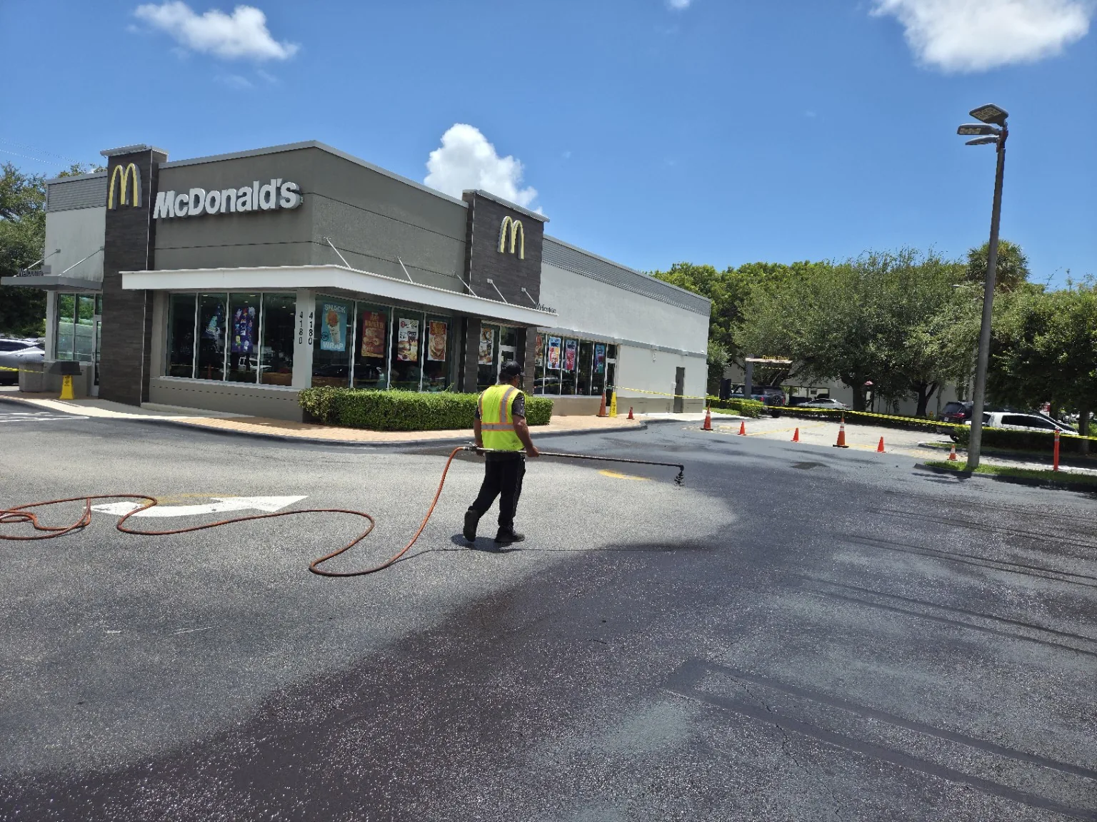 Worker applying sealcoat to a commercial parking lot